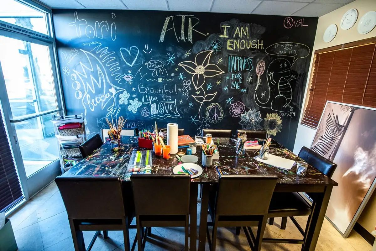An art table with chalkboard wall reading \u201cI am enough\u201d