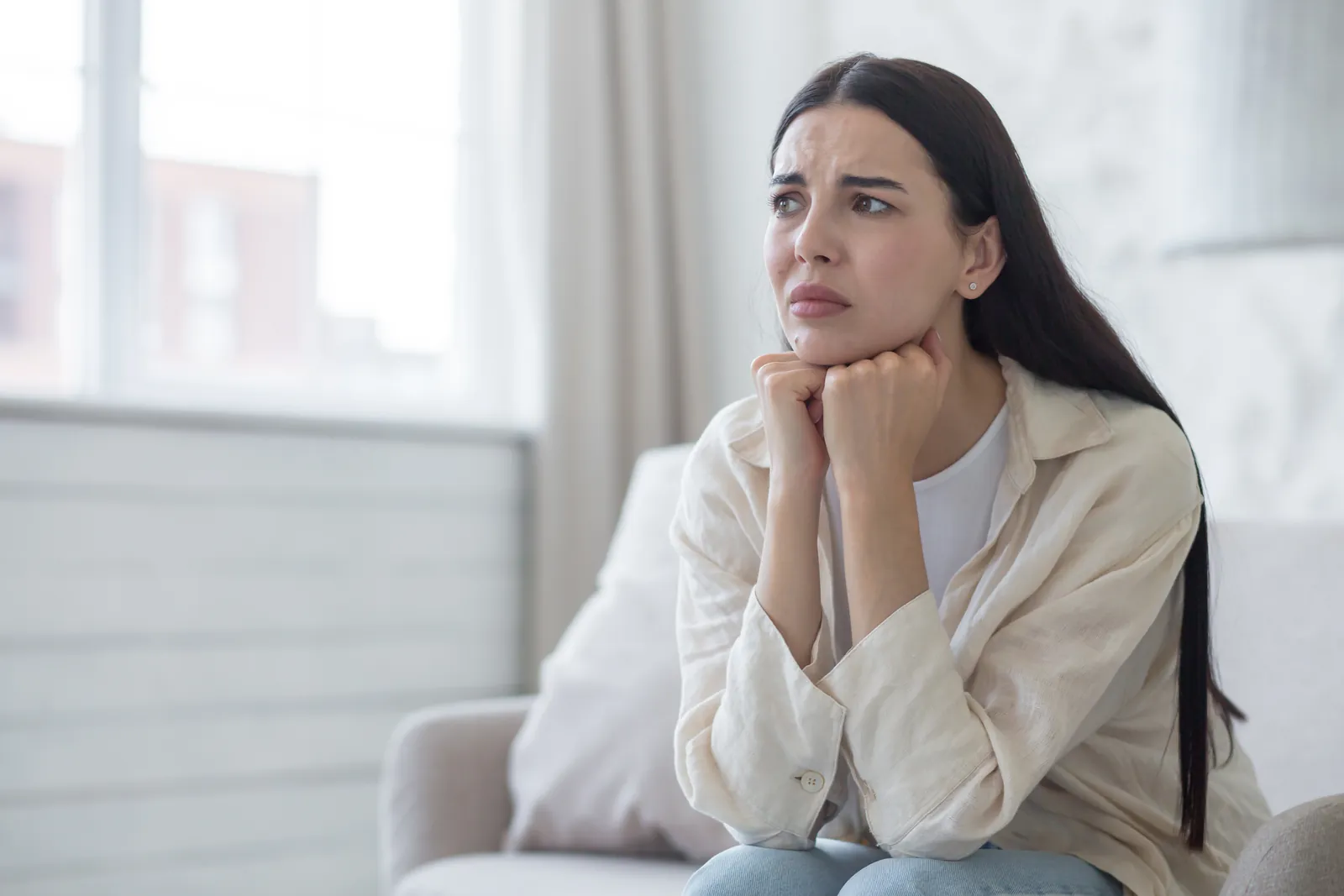 A worried woman sitting on a sofa