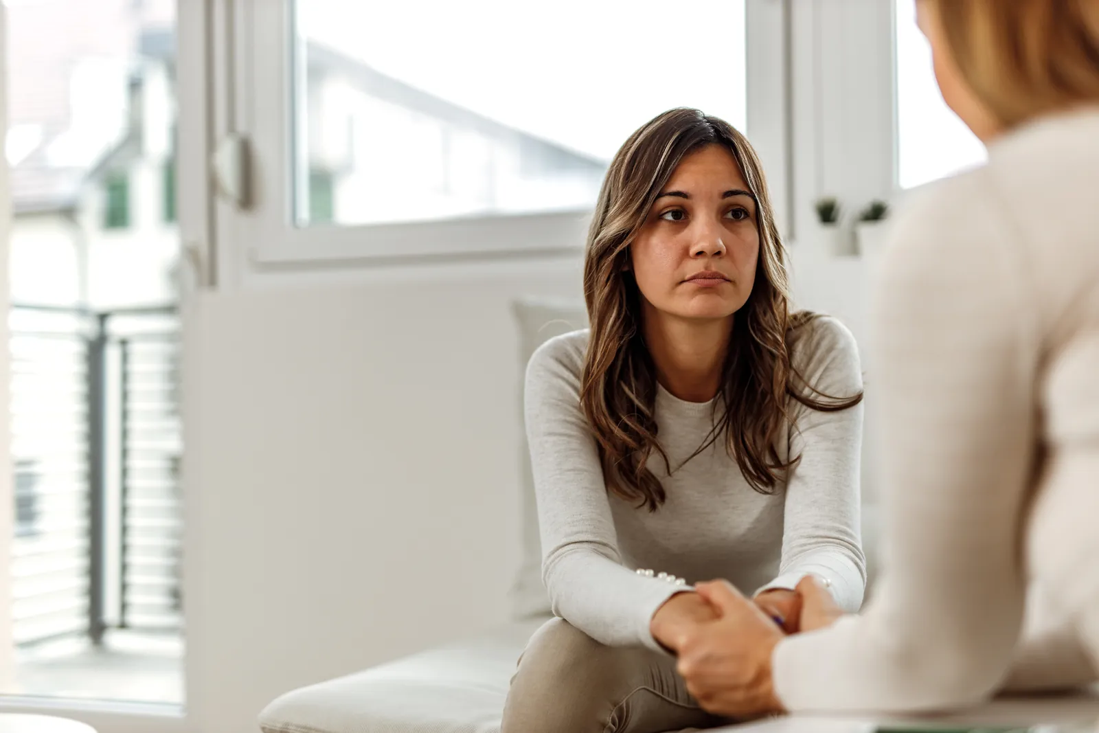 A woman shares her thoughts with another person in a bright room