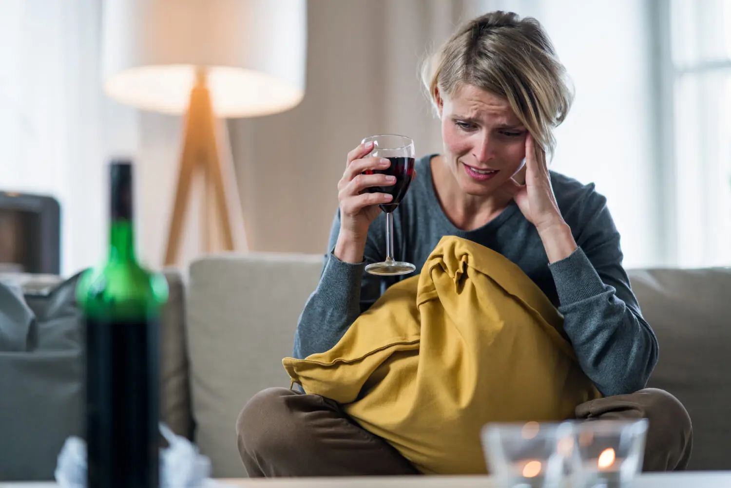 A woman alone with a glass of wine, reflecting the quiet struggle of alcohol use disorder