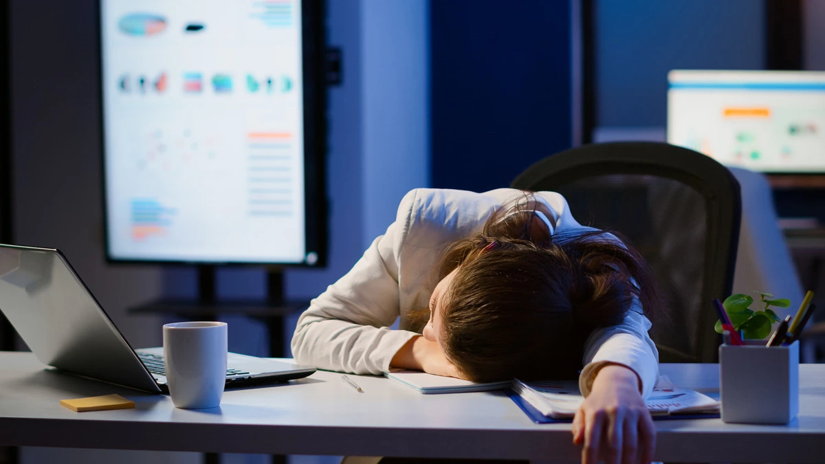 An exhausted woman at her desk, representing stimulant use and burnout in women