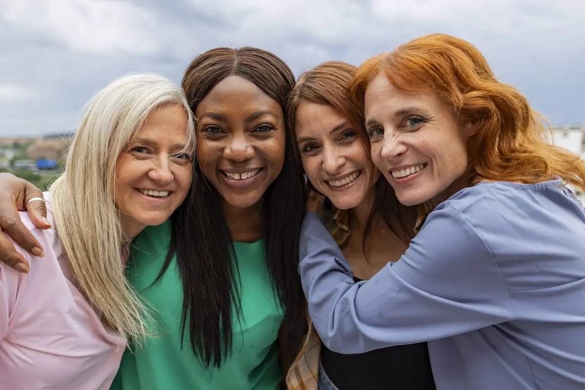 Five women of different backgrounds, smiling together — a women-only recovery community