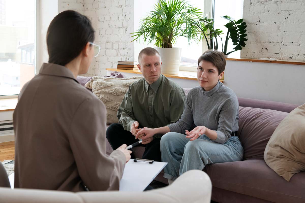 A women's group therapy session in a warm, home-like living room setting