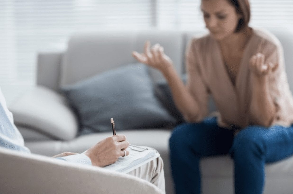 A woman taking notes during a private therapy session