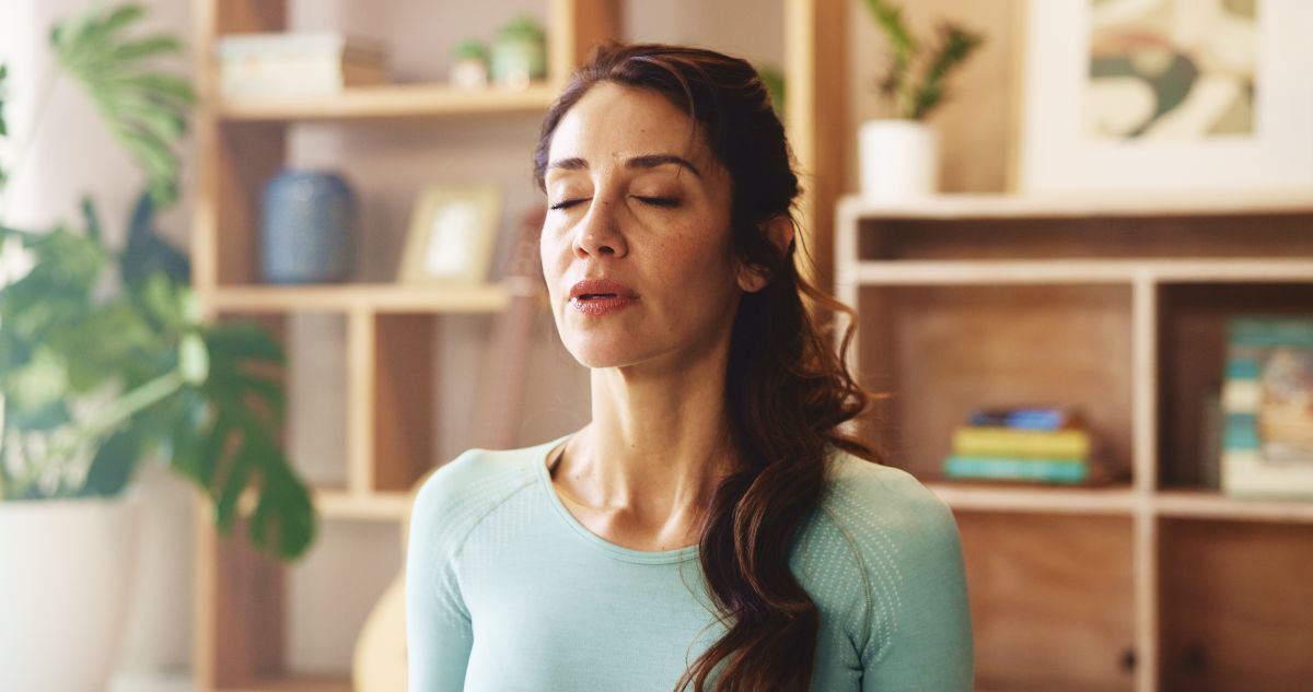 A woman sitting quietly with eyes closed, practicing mindfulness indoors