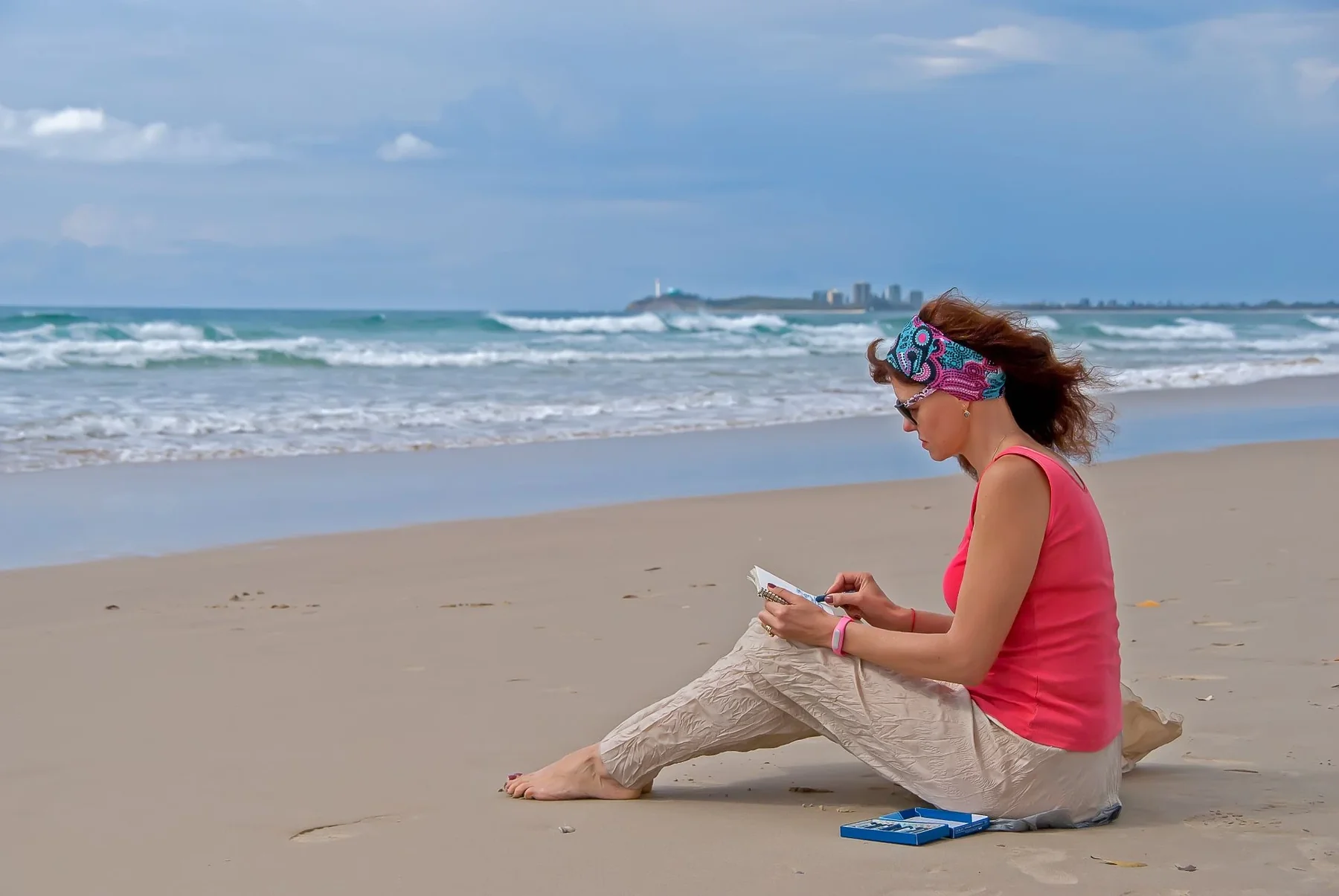 A woman sitting on the beach using a tablet