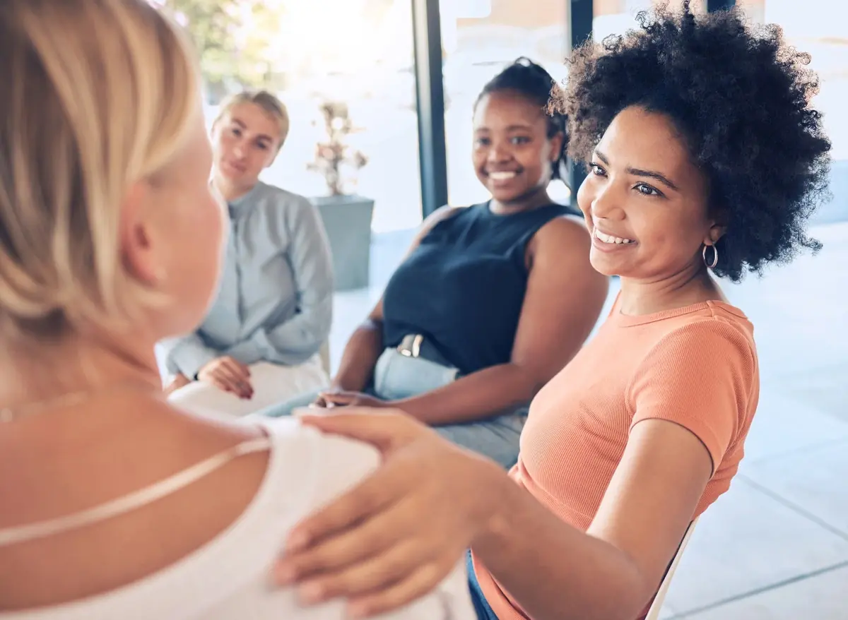 A diverse group of women smiling together in a support group setting
