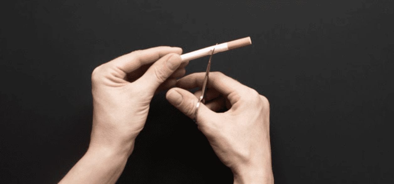 hands cutting a cigarette with scissors