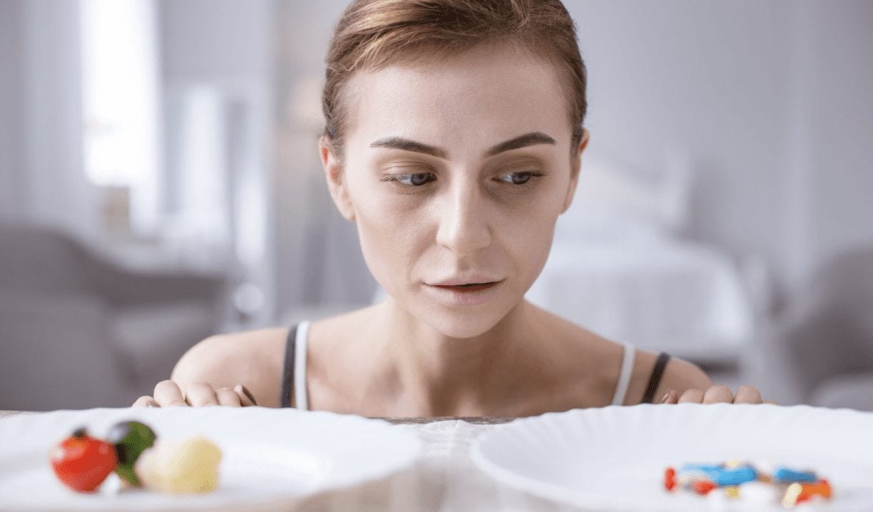 girl with two types of pills on front of her