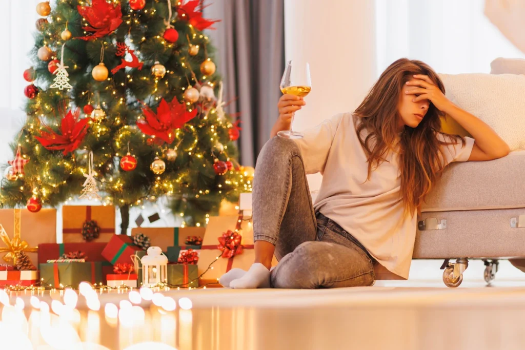 Relapse Risks During the Holiday Season - woman holding a glass of wine infront of a tree