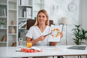 doctor in white coat is indoors with picture of food and vitamins